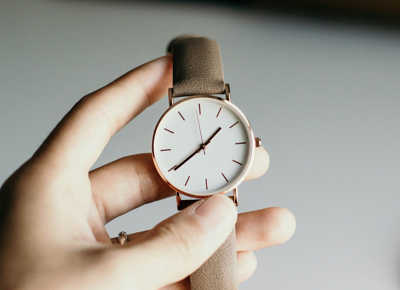 A watch with a leather strap held up to the light before it goes back in the cabinet